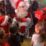 Dzieci wręczają kartkę Mikołajowi.