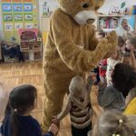 Dzieci przybijają piątkę z misiem