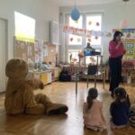 Dzieci i miś słuchają pani