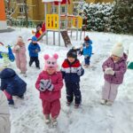 Dzieci na placu zabaw lepią kulki ze śniegu