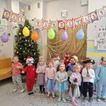 Dzieci pozują do zdjęcia w strojach karnawałowych.