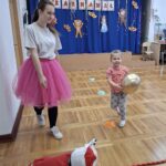 Dziewczynka w asyście nauczyciela biegnie z balonikiem.