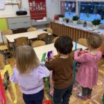 Dzieci zawieszają bibułę na sznurek. Zabawa w małej grupie.